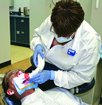 Figure 3 The patient must be positioned to best visualize the correct positioning of the curing light tip. Note the assistant is watching what she is doing through the orange shield on the light guide.